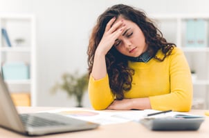 Stressed, unhappy employee sitting at her desk