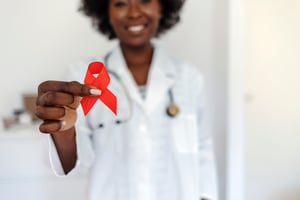 Smiling program member holding up red HIV awareness ribbon after PrEP appointment