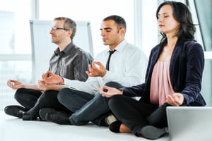 Employees meditating at the office to reduce workplace stress