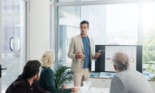 Confident employee leader speaking to table of coworkers