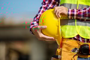 Employee holding safety hard hat and wearing PPE