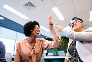 Colleagues high-fiving to celebrate peer accomplishments
