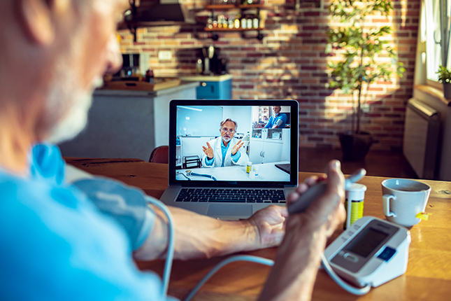 Older man with white hair checking his blood pressure and on a Telehealth appointment 