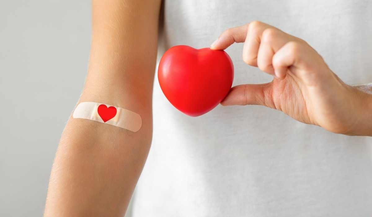 Hand holding heart and showing blood donation bandage