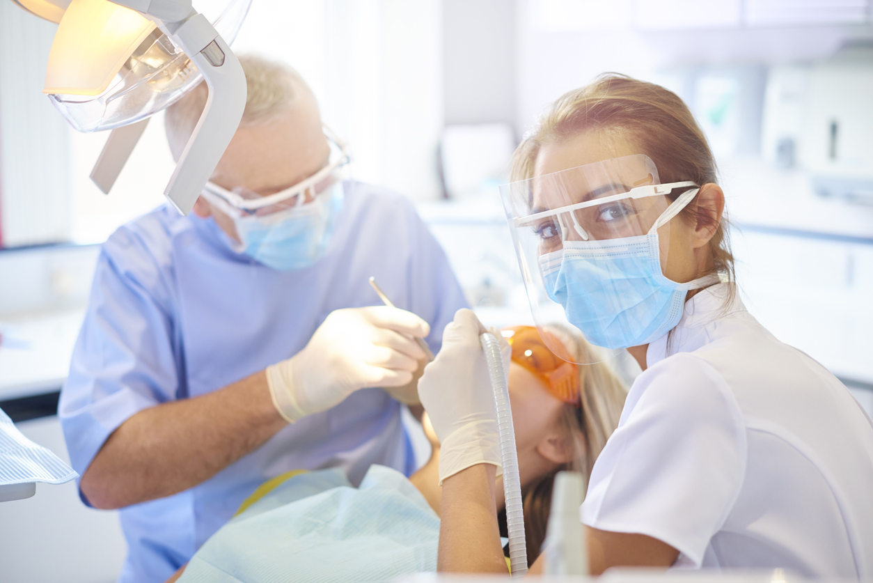 Happy dental assistant working with dentist during procedure