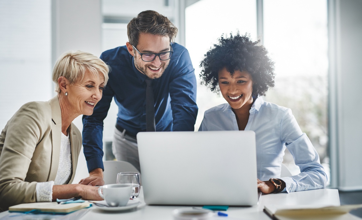 Three motivated employees working together on a laptop