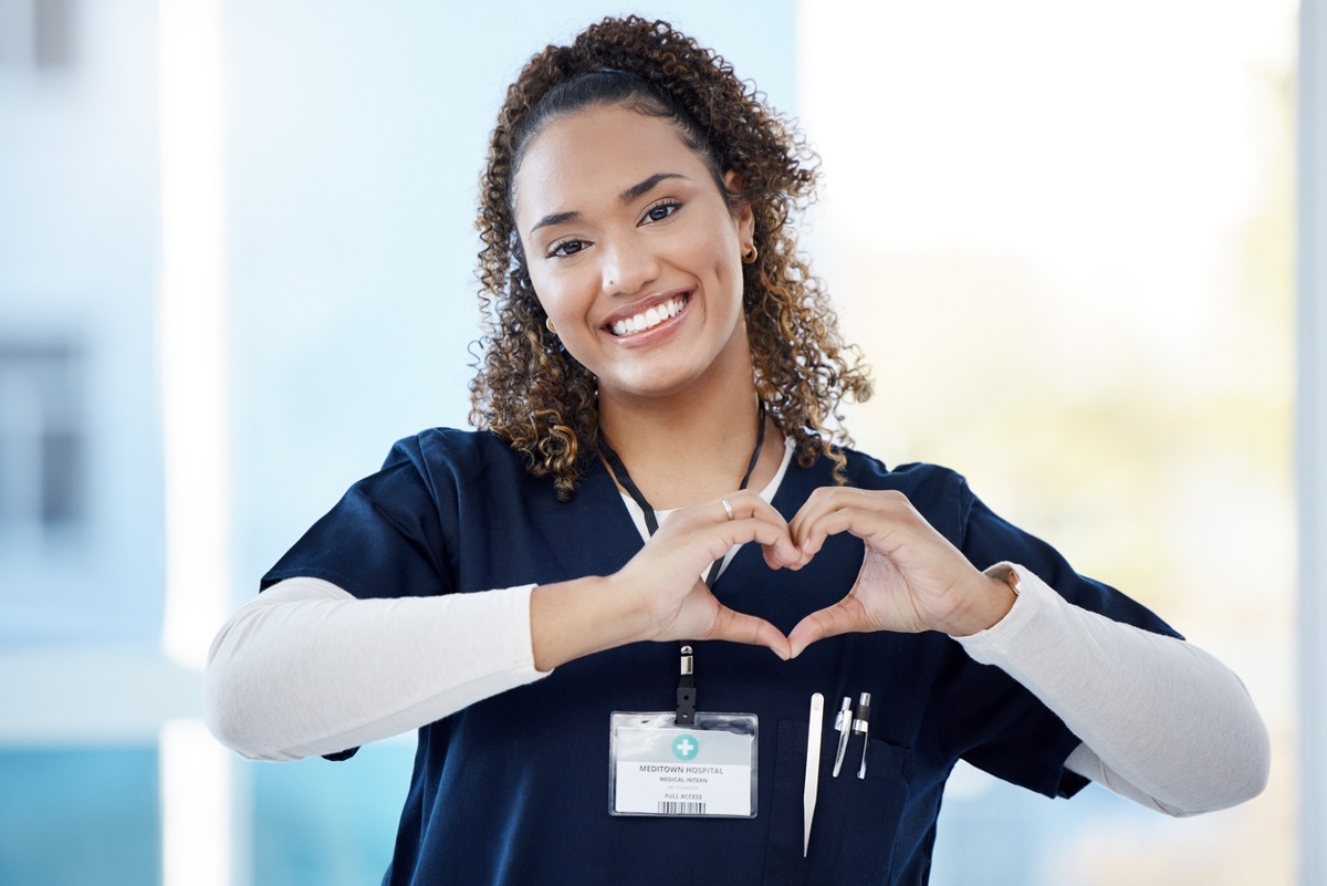 Healthy, happy nurse holding up heart symbol