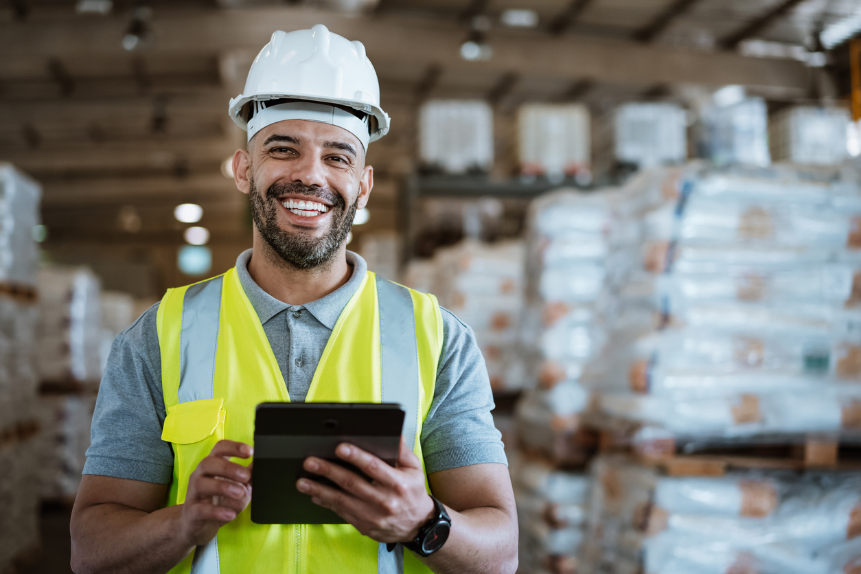 Smiling warehouse employee maintaining workplace safety