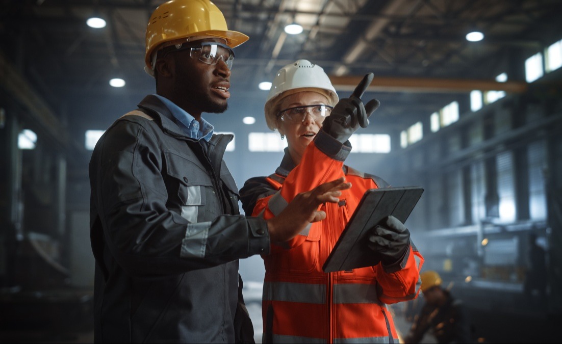 Two employees in PPE discussing safety guidelines